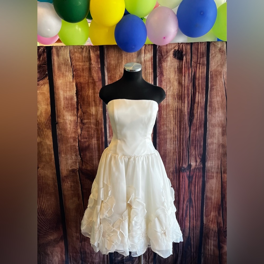 Ivory strapless tea length wedding dress with flowers on the skirt.